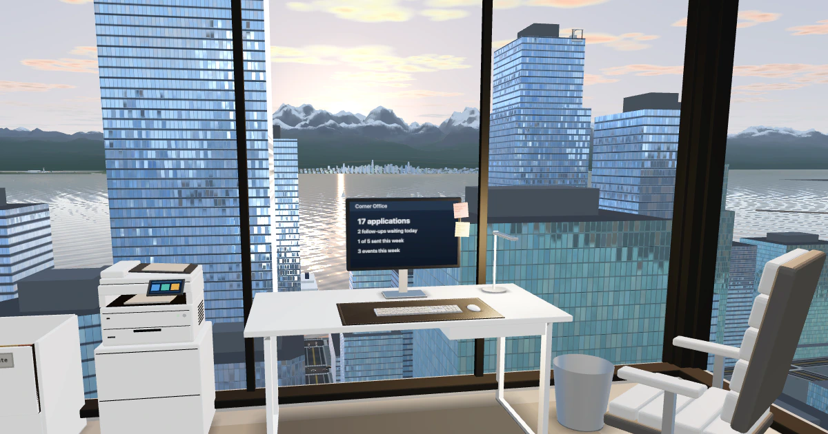 A white desk with a computer and a slim lamp in a corner office high over a city at sunset, floor-to-ceiling windows looking past glass towers to the bay, the sun glittering on the water and snowy mountains beyond.